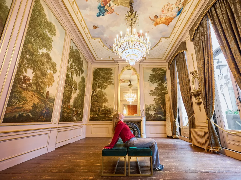 Someone sitting on a bench in the Andriessenkamer looking up in the Grachtenmuseum