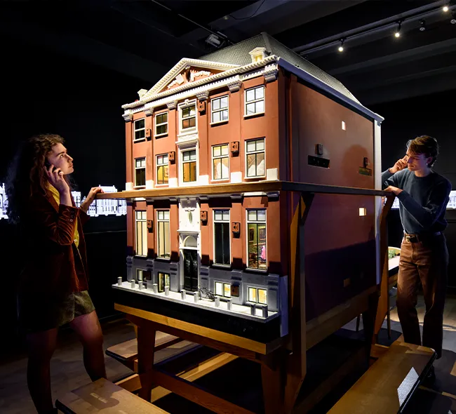 Bezoekers bekijken de maquette van een grachtenpand in de vaste tentoonstelling van het Grachtenmuseum